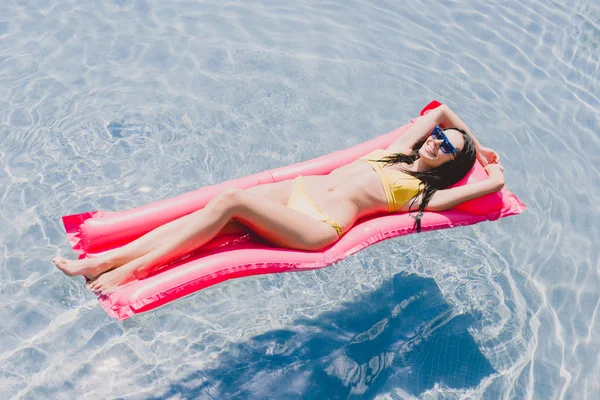 Glückliche brünette Frau liegend auf Schwimmbadschwimmer im Schwimmbad — Stockfoto