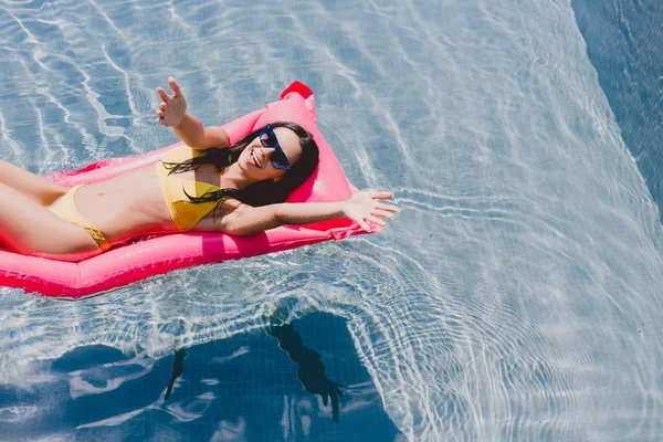 Felice donna bruna con le mani tese sulla piscina galleggiante in piscina — Foto stock