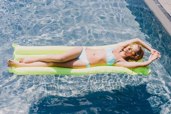 Vista aerea della donna bionda bagnata che nuota sulla piscina verde galleggiante in piscina — Foto stock