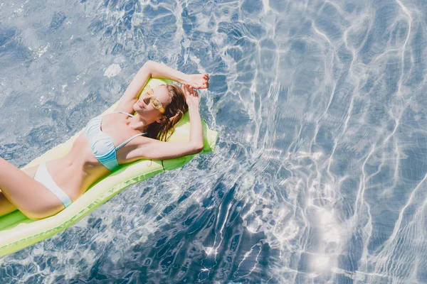 Vue aérienne de femme sexy blonde humide nageant sur flotteur de piscine verte dans la piscine — Photo de stock