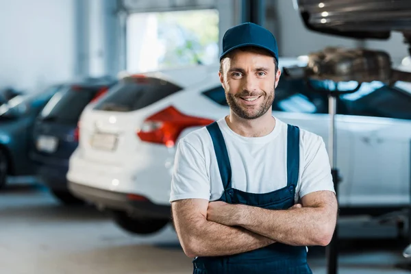 Mecánico feliz coche de pie con los brazos cruzados en el servicio de coche - foto de stock