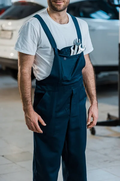 Abgeschnittene Ansicht eines glücklichen Automechanikers, der mit Handschlüsseln in der Tasche steht — Stockfoto