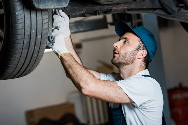 Handsome car mechanic repairing automobile in car service — Stock Photo