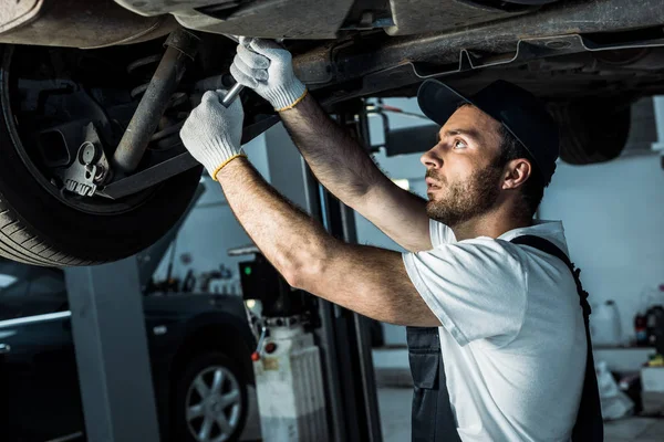 Bärtige Automechaniker in Mütze Reparatur Auto im Auto-Service — Stockfoto