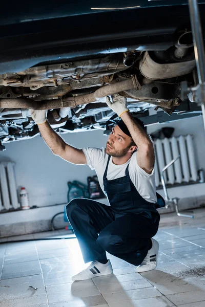 Selective focus of bearded car mechanic repairing automobile — Stock Photo