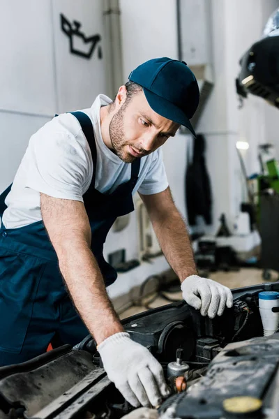 Foco seletivo do reparador em luvas olhando para o motor do carro — Fotografia de Stock