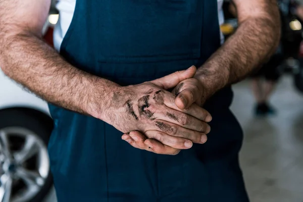 Cropped view of car mechanic standing with mud on clenched hands — Stock Photo