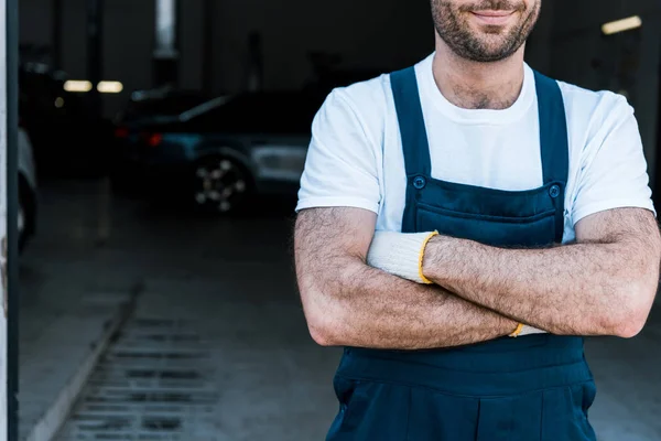 Vue recadrée de heureux mécanicien de voiture barbu debout avec les bras croisés — Photo de stock