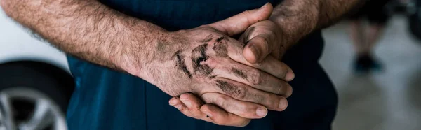 Panoramic shot of car mechanic standing with mud on clenched hands — Stock Photo