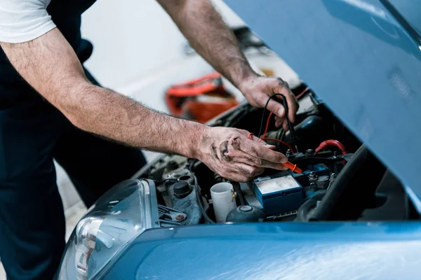 Corte vista auto mecânico com lama nas mãos fixação automóvel na estação de reparação de automóveis — Fotografia de Stock