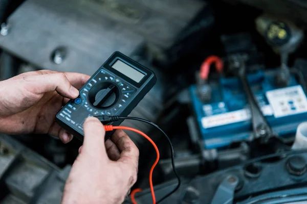 Cropped view of car mechanic holding measuring device in car service — Stock Photo