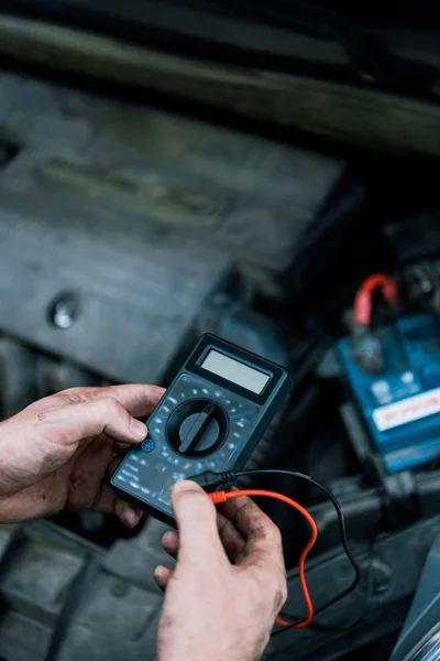 Cropped view of auto mechanic holding measuring device in car service — Stock Photo