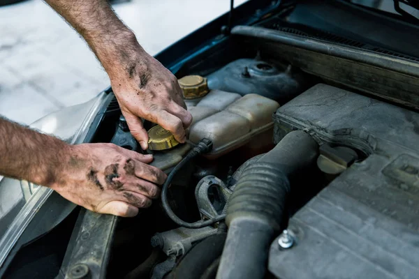 Vista ritagliata del meccanico automatico con fango sulle mani che cambiano olio per auto — Foto stock