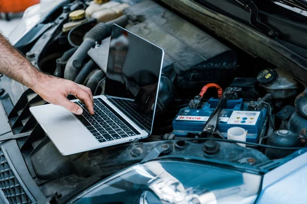 Vista cortada do mecânico do carro usando laptop com tela em branco perto do carro — Fotografia de Stock