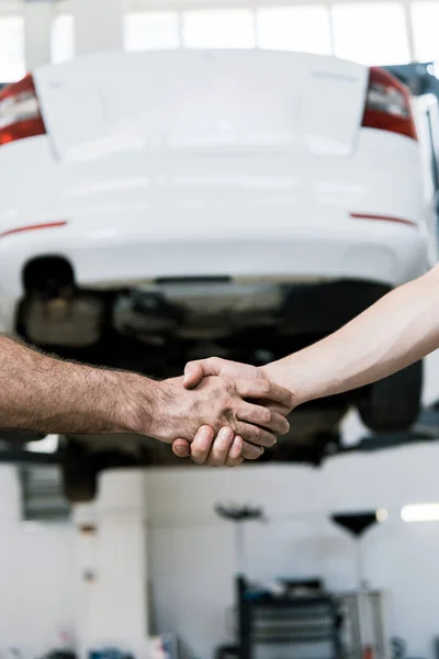 Vista ritagliata del meccanico auto stringendo la mano con l'uomo in garage — Foto stock