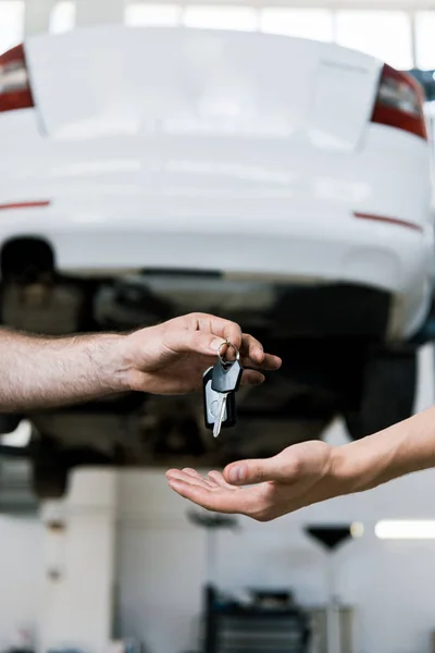 Visão cortada do carro mecânico dando a chave para o homem na garagem — Fotografia de Stock