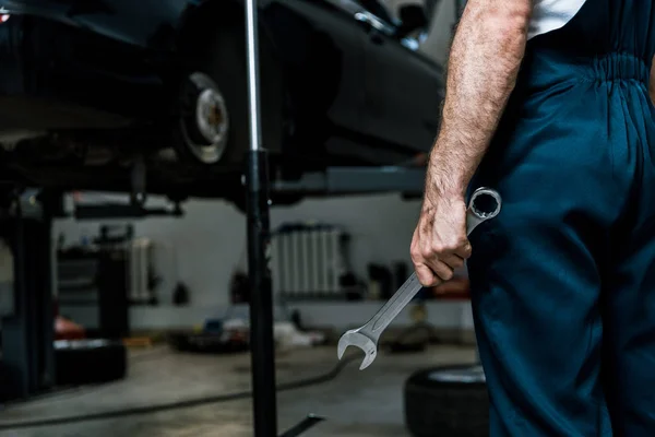 Cropped view of car mechanic holding hand wrench in car repair station — Stock Photo