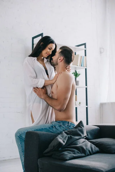 Attractive and brunette woman in shirt hugging with shirtless man — Stock Photo