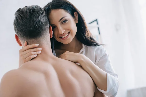Attractive and brunette woman in shirt hugging with shirtless man — Stock Photo