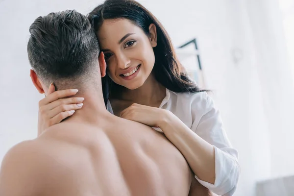 Attrayant et brunette femme en chemise câlin avec homme torse nu — Photo de stock