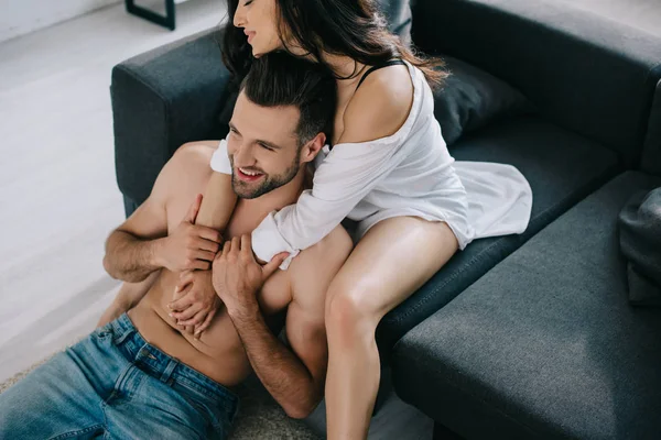 Atractiva y morena mujer en camisa abrazándose con el hombre muscular - foto de stock