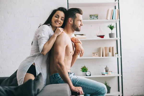 Mulher atraente e sorridente com olhos fechados na camisa abraçando com homem bonito — Fotografia de Stock