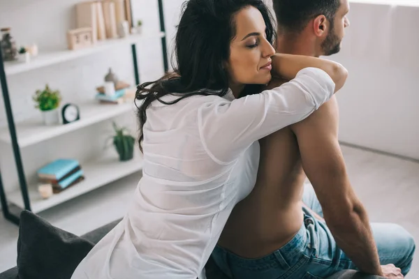 Attractive and brunette woman with closed eyes in shirt hugging with man — Stock Photo