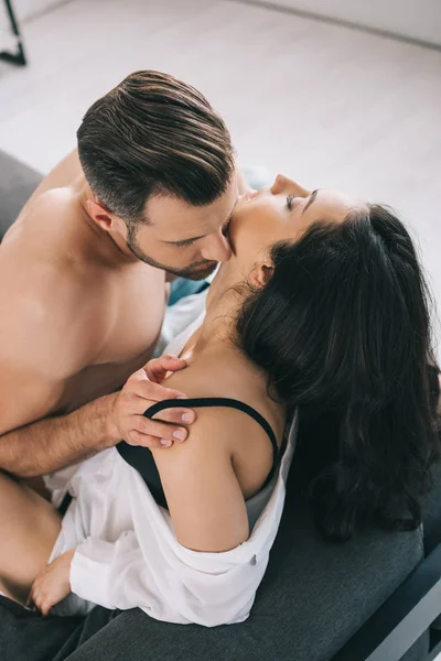 Hochwinkelaufnahme eines hemdlosen und gutaussehenden Mannes, der eine brünette Frau küsst — Stockfoto