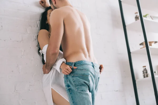Low angle view of sexy man hugging and kissing with woman near wall — Stock Photo