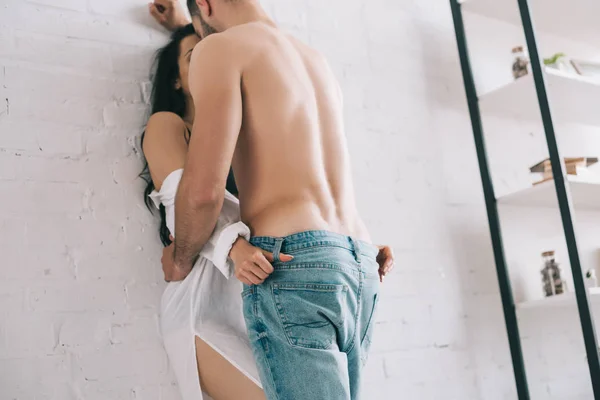 Vista de ángulo bajo de hombre sexy abrazos y besos con mujer cerca de la pared - foto de stock