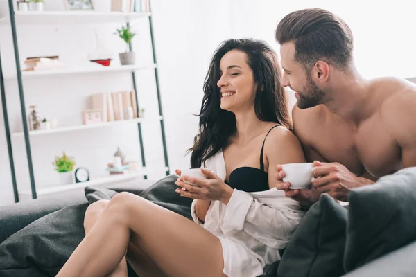 Handsome man and attractive woman in bra holding cups and smiling — Stock Photo