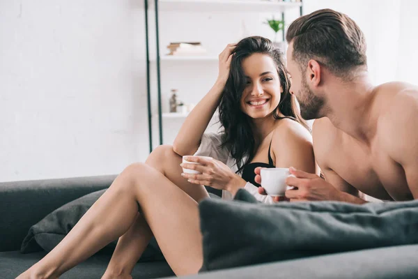 Homem sexy e mulher atraente segurando copos com café e sorrindo — Fotografia de Stock