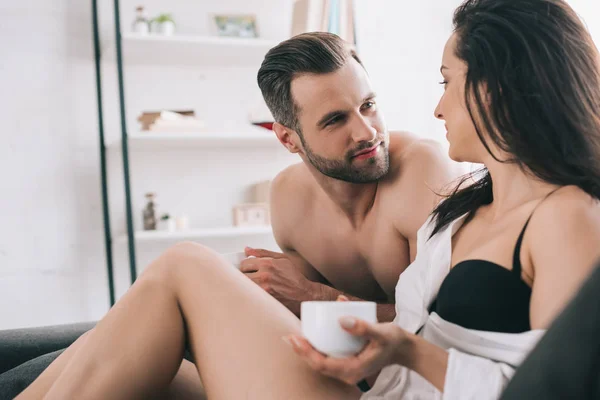 Handsome man and sexy woman in bra holding cup and looking at each other — Stock Photo