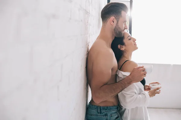 Side view of handsome man and sexy woman holding cups — Stock Photo