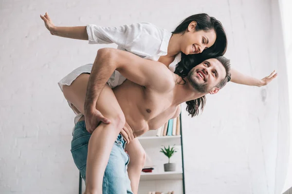 Bel homme en jeans et femme souriante en chemise jouant — Photo de stock