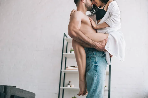 Cropped view of man in jeans holding and kissing with sexy woman — Stock Photo