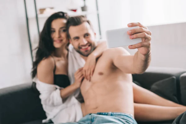 Handsome man and sexy woman in shirt and bra smiling and taking selfie — Stock Photo