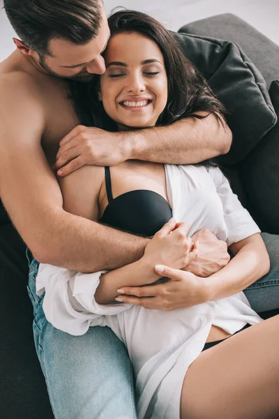 Hombre guapo y mujer sexy en camisa y sujetador acostado y abrazando - foto de stock