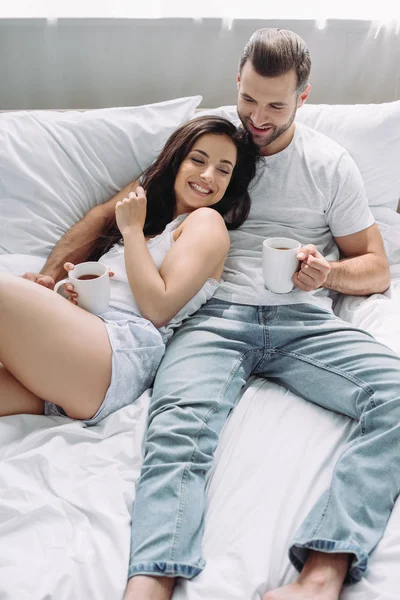 Attractive and brunette woman and man lying on bed and hugging — Stock Photo