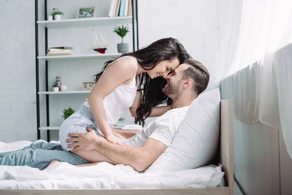 Attractive and brunette woman sitting on man and smiling — Stock Photo