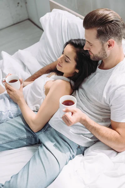 Attractive and brunette woman and man holding cups and hugging — Stock Photo