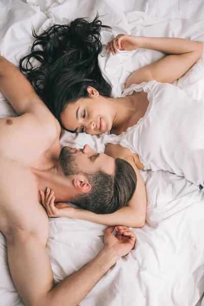 Vista dall'alto di uomo bello e senza maglietta sdraiato con donna attraente sul letto — Foto stock