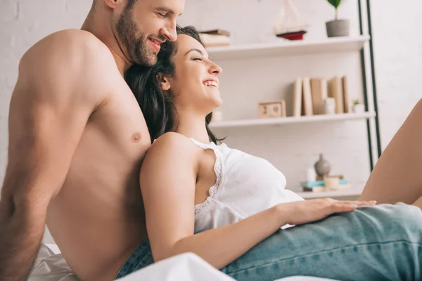 Vista lateral de mujer atractiva con los ojos cerrados y hombre guapo sonriendo en el dormitorio - foto de stock