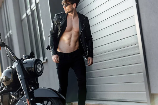 Joven con torso muscular desnudo caminando cerca de la motocicleta - foto de stock