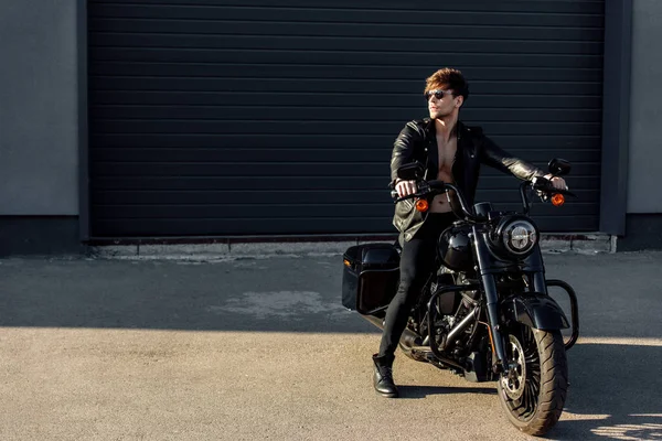 Повна довжина красивого чоловіка з голим торсом, сидячи на мотоциклі і дивлячись — стокове фото