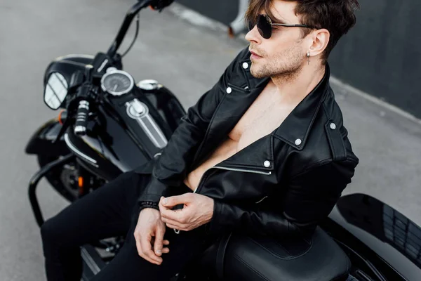 Schöner Motorradfahrer mit nacktem Oberkörper auf Motorrad gestützt — Stockfoto