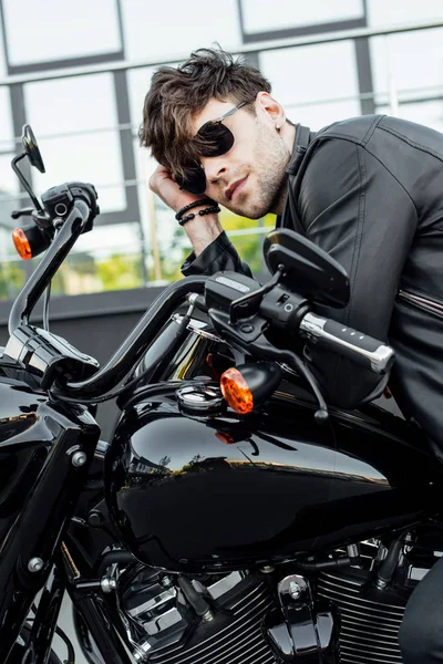 Beau jeune homme en veste en cuir reposant tout en étant assis sur la moto — Photo de stock