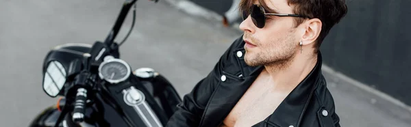 Panoramic shot of handsome motorcyclist with naked torso leaning on motorcycle — Stock Photo