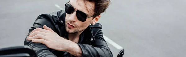 Panoramic shot of cool man in sunglasses sitting on motorcycle and looking away — Stock Photo