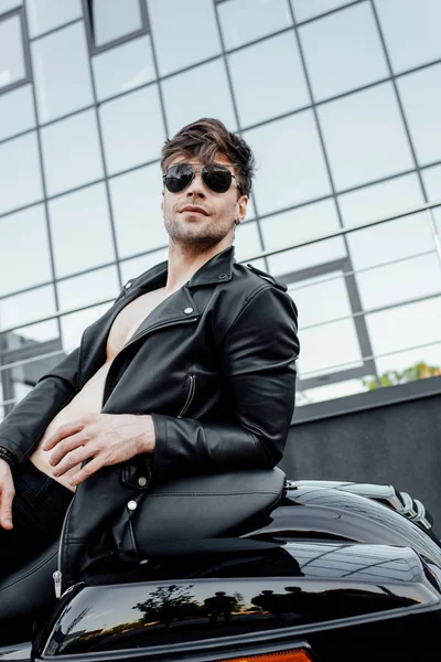 Sexy Motorradfahrerin mit Sonnenbrille lehnt am Motorrad und schaut weg — Stockfoto